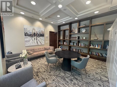 A living room with a large painting on the wall and a bookshelf filled with books.