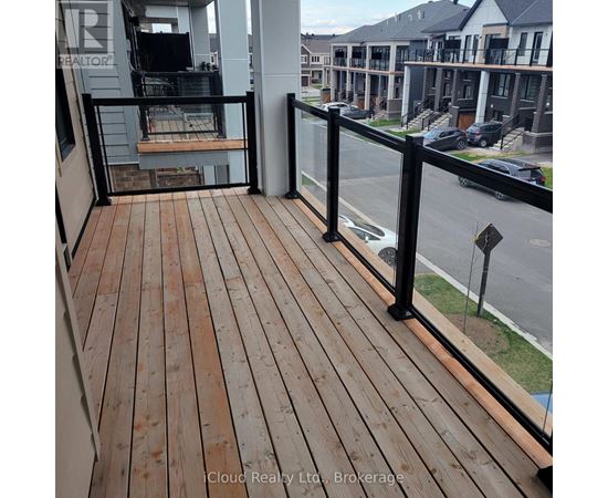 A balcony with a wooden floor and black railings overlooks a street.