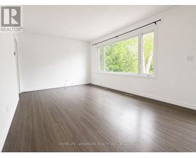 A room with wooden flooring and a window overlooking trees.