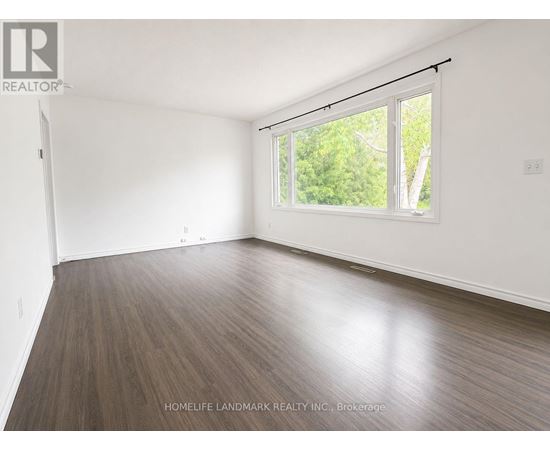 A room with wooden flooring and a window overlooking trees.