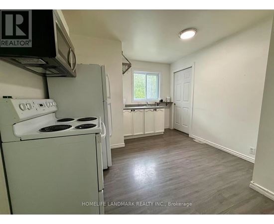 A small, clean kitchen with a white stove and cabinets.