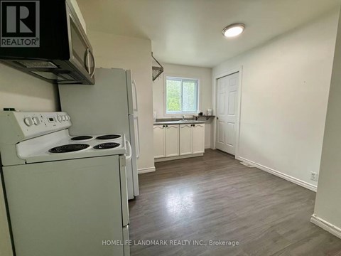 A small, clean kitchen with a white stove and cabinets.