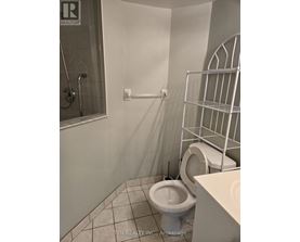 A white toilet in a small bathroom with a walk-in shower.
