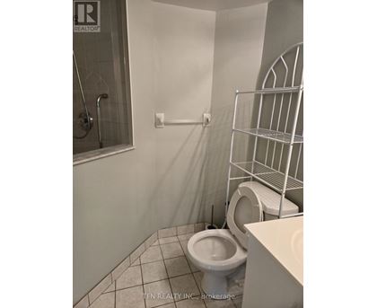 A white toilet in a small bathroom with a walk-in shower.