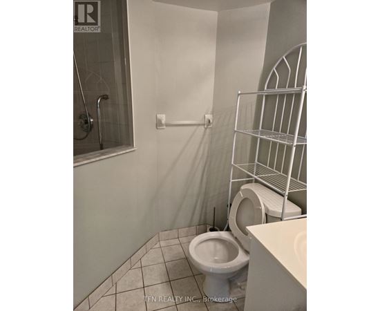 A white toilet in a small bathroom with a walk-in shower.