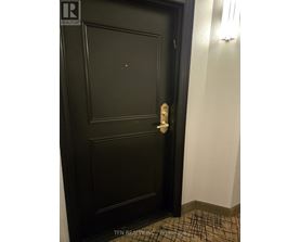A black door with a white handle and a brochure on the floor.