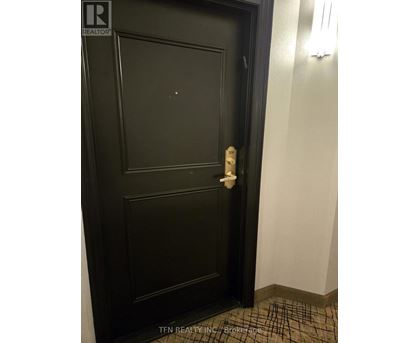 A black door with a white handle and a brochure on the floor.