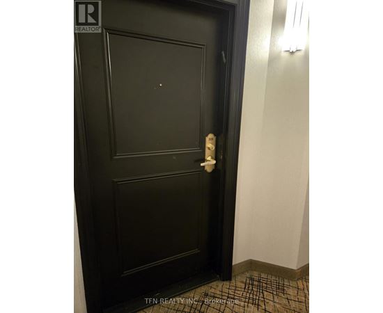 A black door with a white handle and a brochure on the floor.