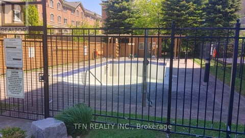 A pool surrounded by a black fence with a sign that says TFN Realty INC., Brokerage.