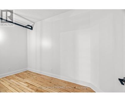 A room with wooden flooring and white walls.