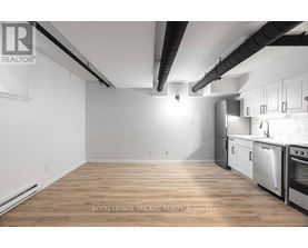 A well-lit kitchen with wooden floors and stainless steel appliances.