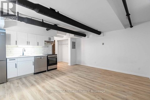 A spacious kitchen with white cabinets and a wooden floor.