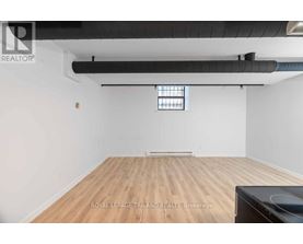 A spacious room with wooden flooring and a window.