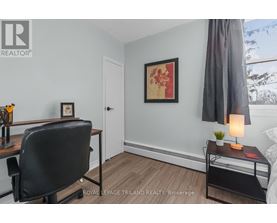 A room with a black chair and a painting on the wall.