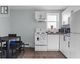 A kitchen with white appliances and a table with chairs.