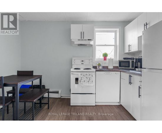 A kitchen with white appliances and a table with chairs.