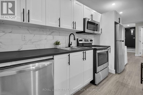 A kitchen with white cabinets and black countertops.