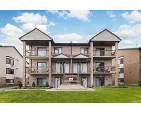 A large two-story apartment building with a front lawn.