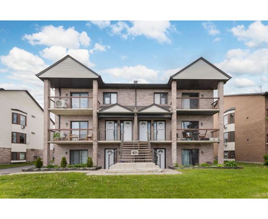 A large two-story apartment building with a front lawn.