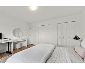 A bedroom with a large bed and a desk with a mirror.