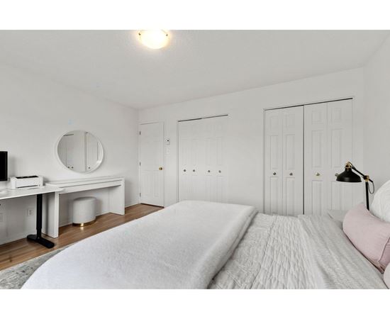A bedroom with a large bed and a desk with a mirror.