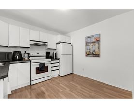 A kitchen with white cabinets and a wooden floor.