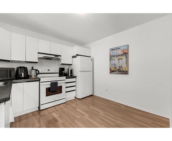 A kitchen with white cabinets and a wooden floor.