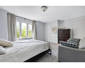 A bedroom with a large bed and a grey couch.