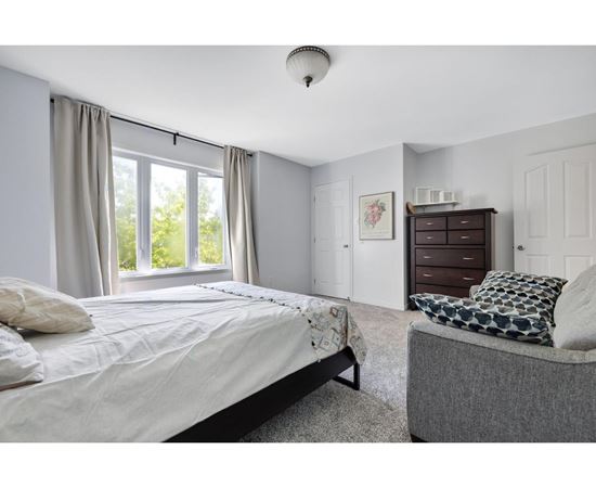 A bedroom with a large bed and a grey couch.