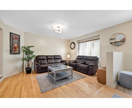 A living room with a brown leather couch and a glass coffee table.