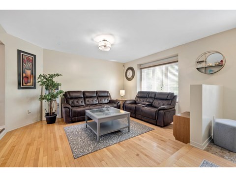 A living room with a brown leather couch and a glass coffee table.