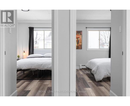 A bedroom with two beds and a painting on the wall.