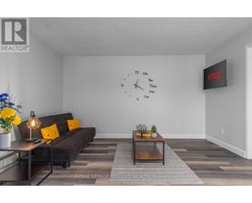 A living room with a couch, coffee table, and a clock on the wall.