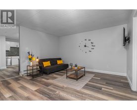 A living room with a couch, coffee table, and a clock on the wall.