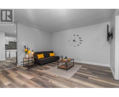 A living room with a couch, coffee table, and a clock on the wall.