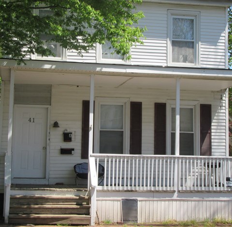 A white house with a porch and a mailbox on the front door.