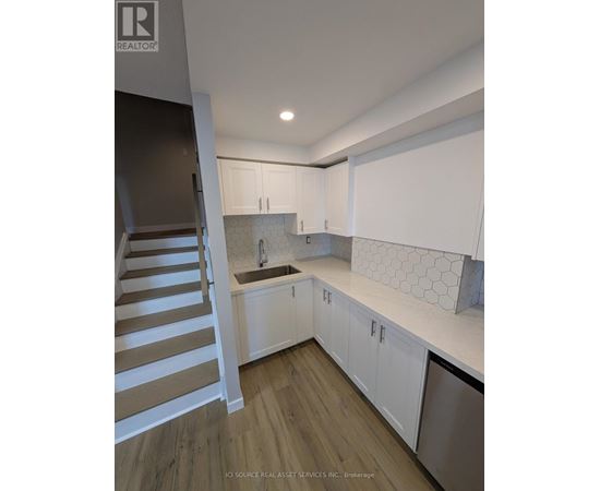 A kitchen with white cabinets and a wooden staircase.