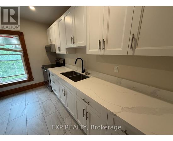 A kitchen with white cabinets and a marble countertop.
