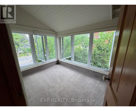 A sunny room with a carpet floor and a view of trees outside.