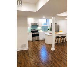 A kitchen with white cabinets and a wooden floor.