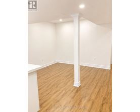 A room with a white column and wooden flooring.