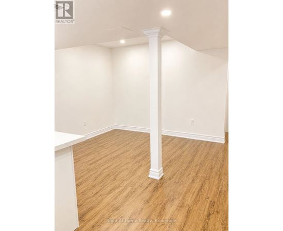 A room with a white column and wooden flooring.