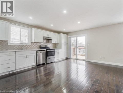 A spacious kitchen with white cabinets and a checkered backsplash.