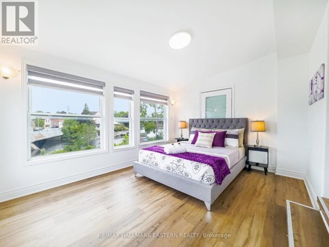 A bedroom with a large bed and a view of the outside through the windows.
