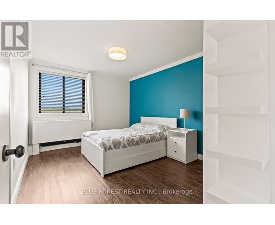 A bedroom with a bed, nightstand, and window.