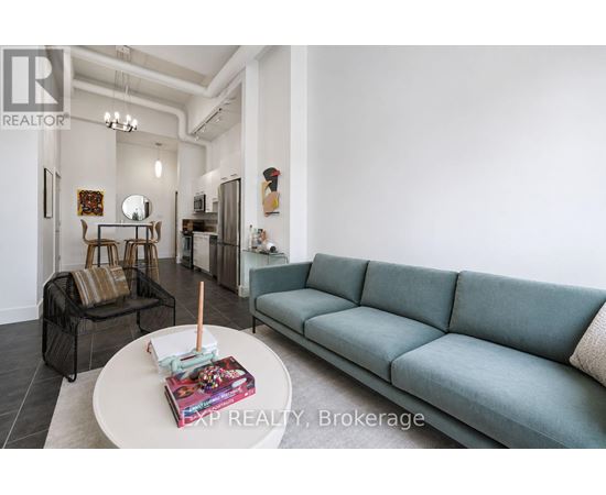 A living room with a grey couch and a coffee table with a book and a candle on it.