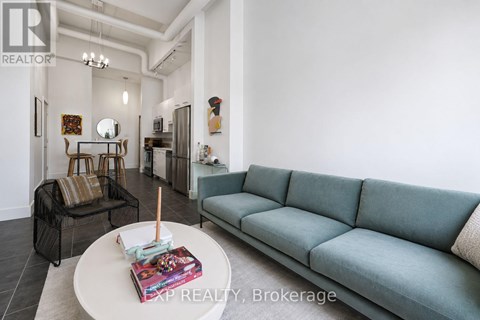 A living room with a grey couch and a coffee table with a book and a candle on it.