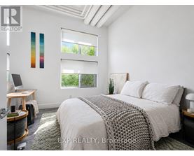 A bedroom with a bed, desk, and window with blinds.