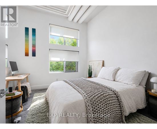 A bedroom with a bed, desk, and window with blinds.