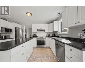 A kitchen with white cabinets and black countertops.